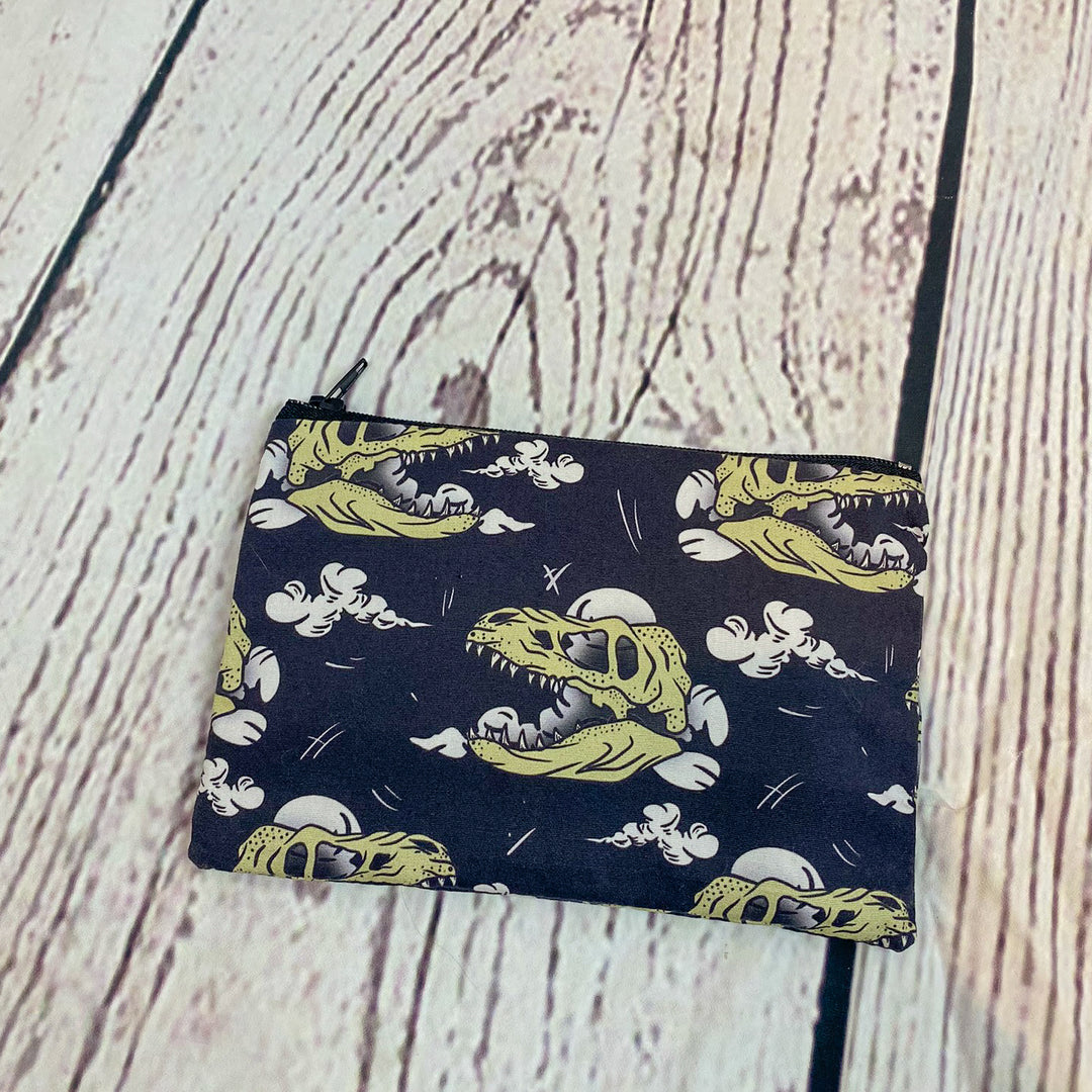 a small zipper bag with a pattern of dinosaurs on it