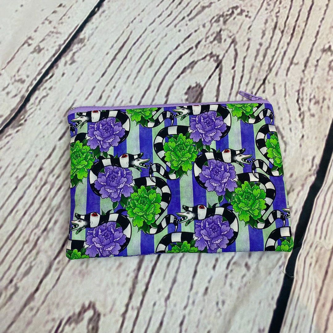 a purple and green purse sitting on top of a wooden table