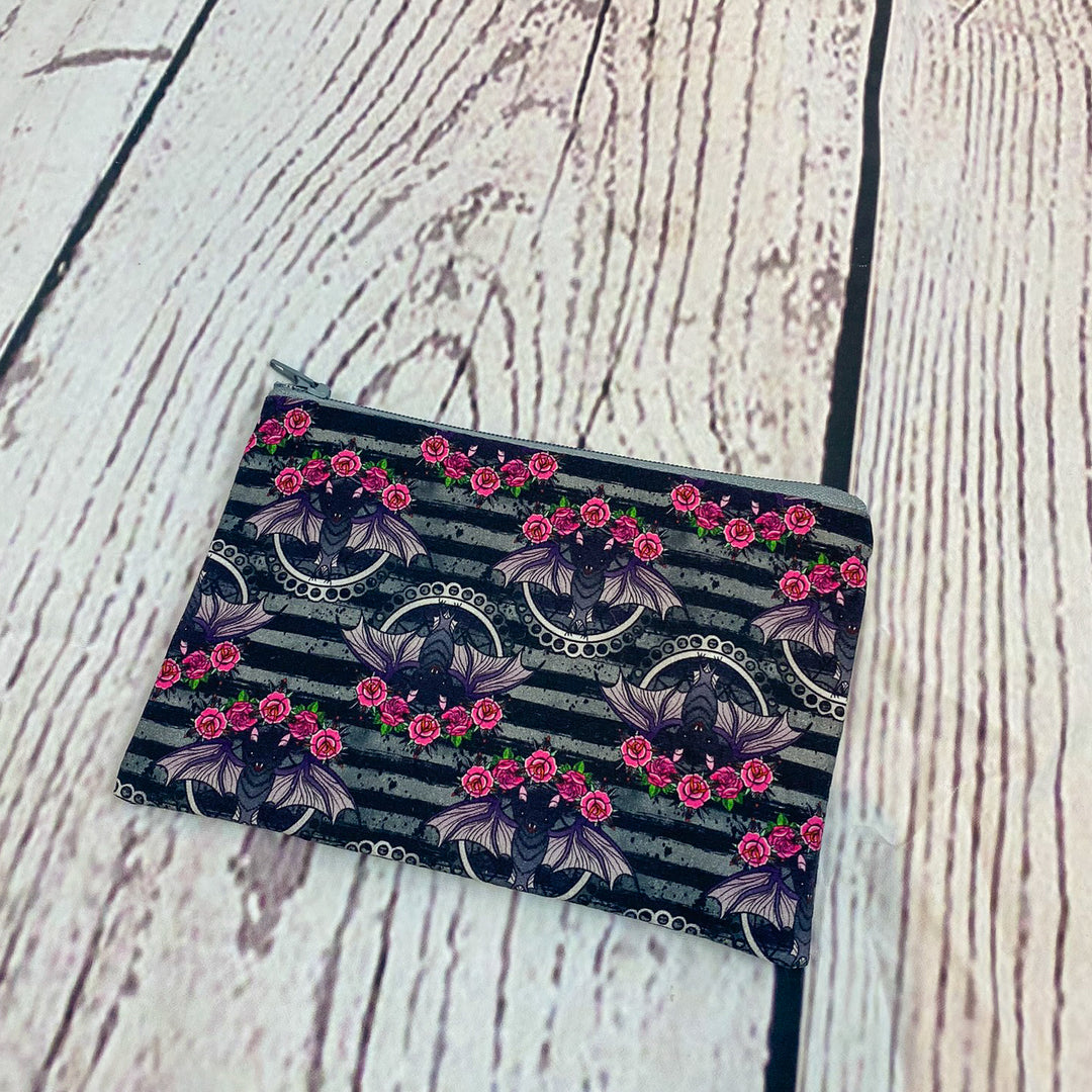 a black and pink flowered wallet sitting on top of a wooden floor